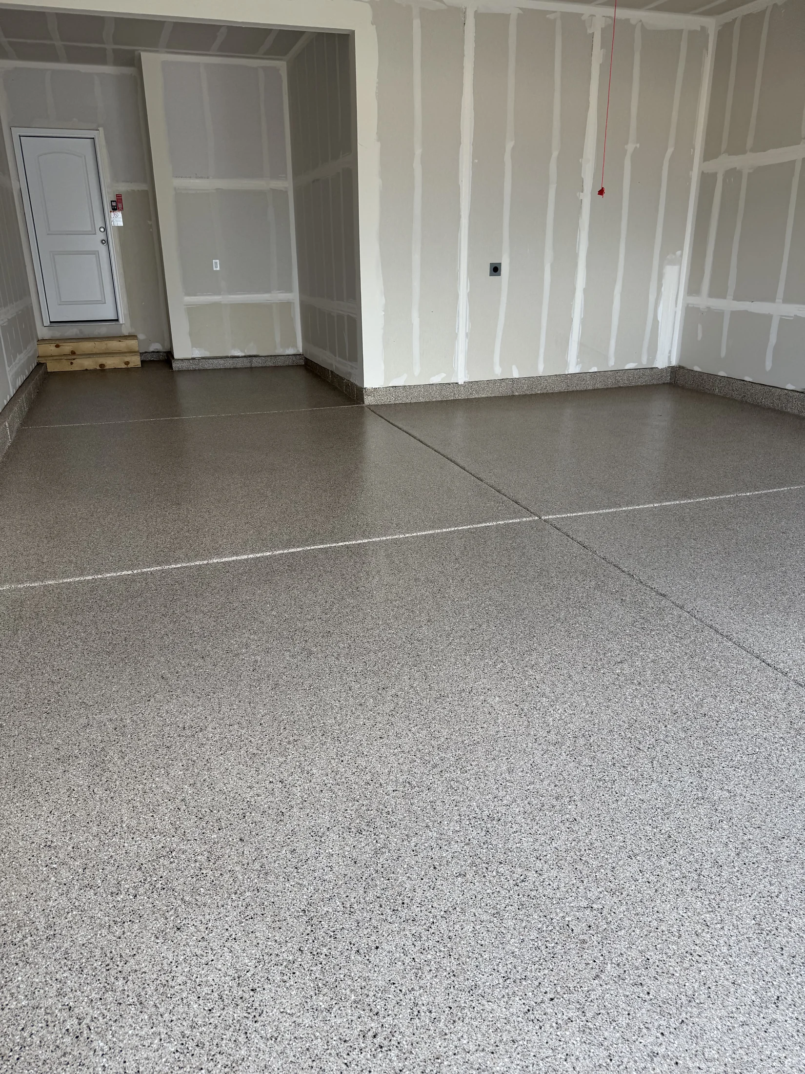 Tan decorative flake garage floor with coated perimeter stem walls