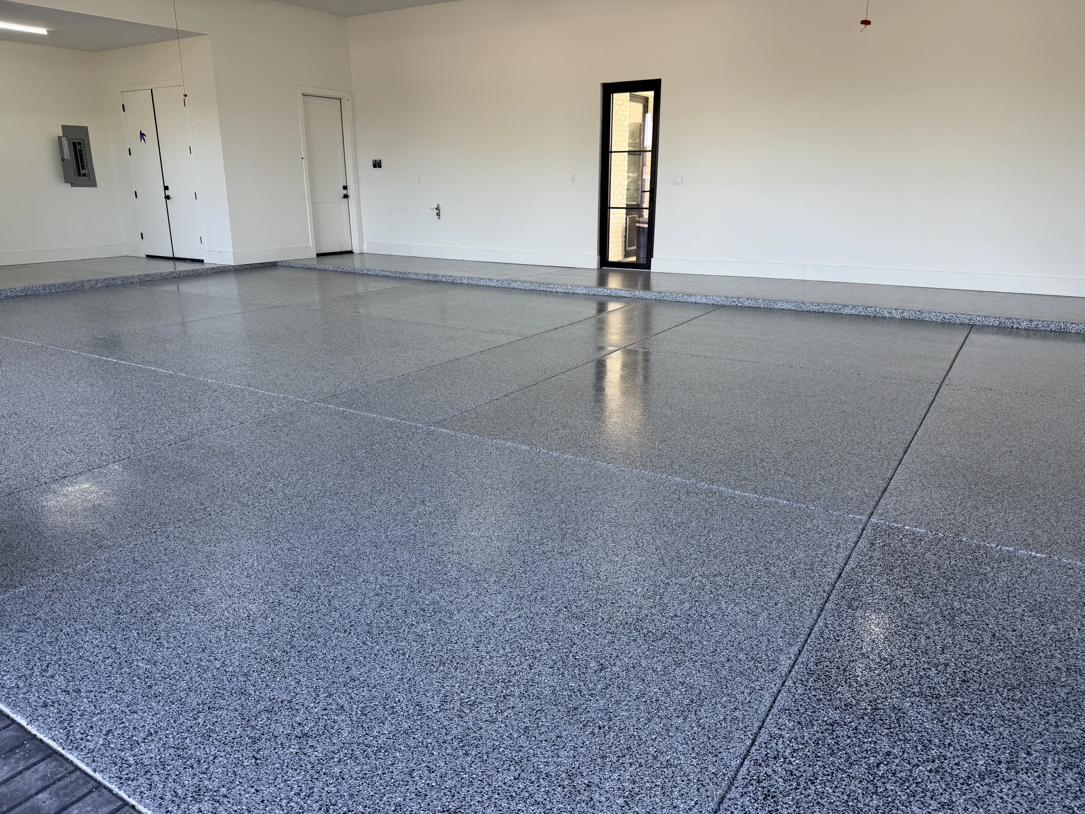 Glossy gray decorative flake coating across a spacious multi-car garage