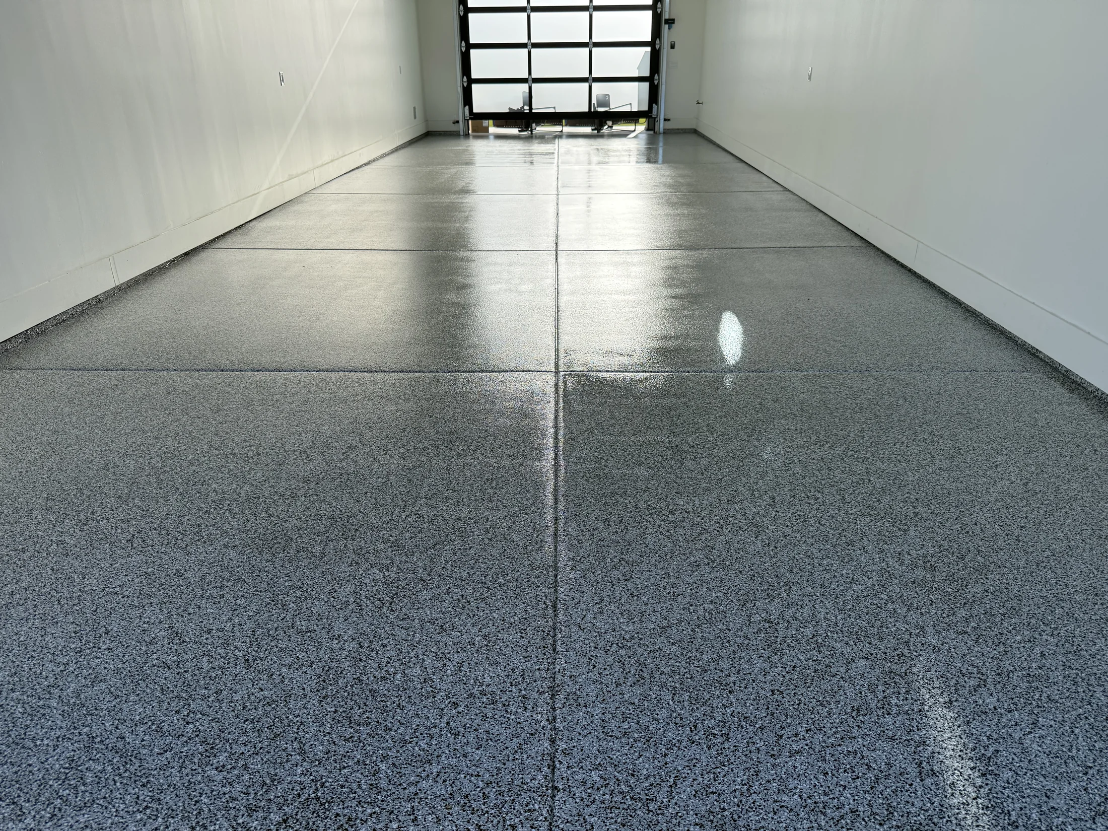 Glossy gray decorative flake floor in a bright garage with a glass-panel door